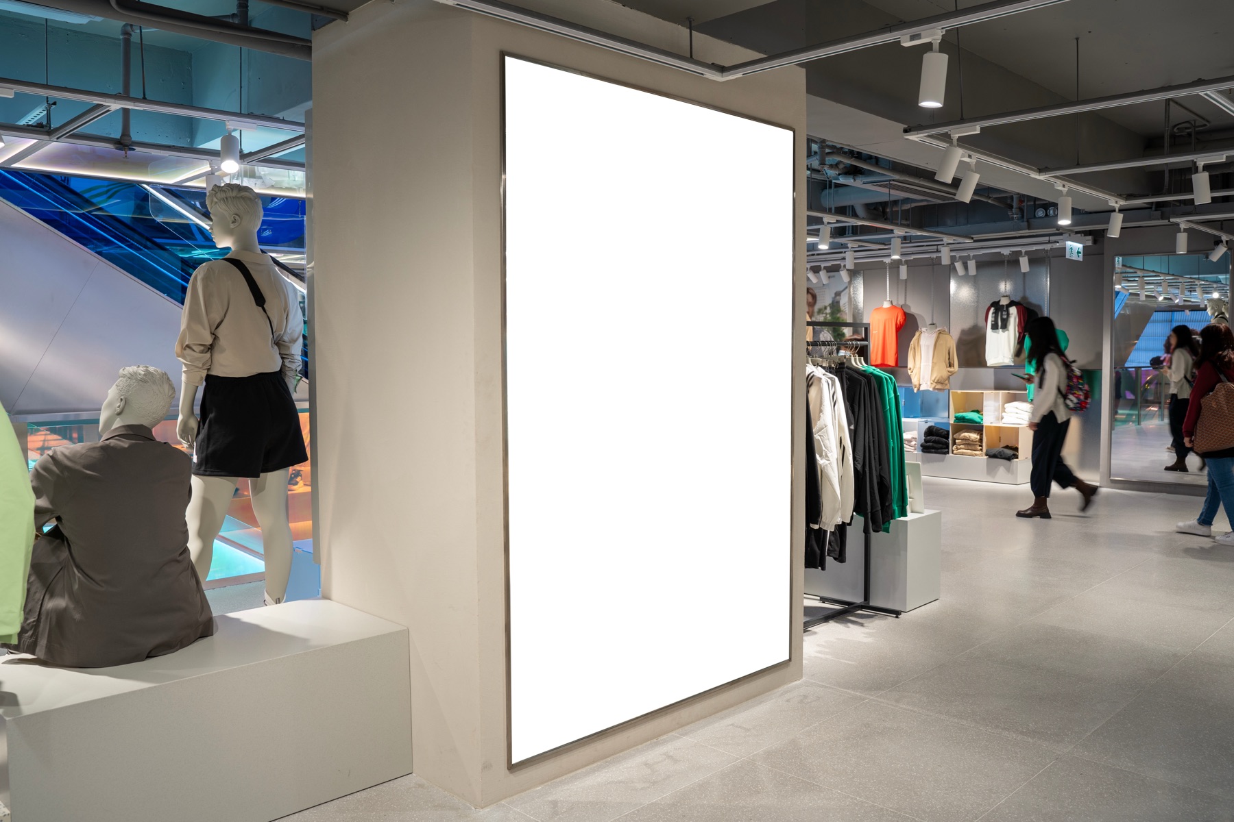 Vertical LED display panel in a retail flagship store, among mannequins and merchandise